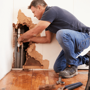 man repairs burst water pipe