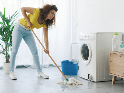 Washing machine leaking and woman cleaning with mop